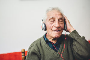 An old man in his 80s listening to his music on a new headset
